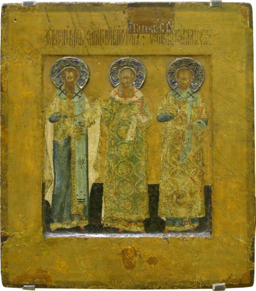 Доска: Две врезные встречные шпонки.
Изображены трое святых в рост, в священническом одеянии. Над головами финифтевые венчики. Икона с выемкой.
