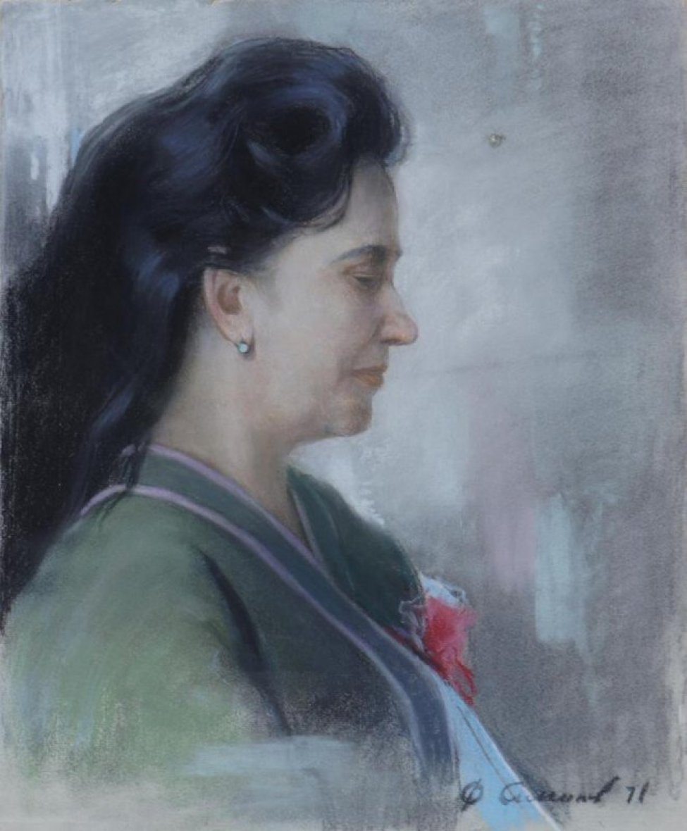 Погрудное изображение женщины в профиль, с зачесанными назад черными длинными волосами, в зеленой кофте с сиреневой отделкой, голубой блузке, с ярким красно-розовым цветком на груди.