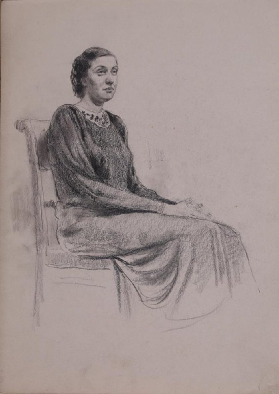 В 3/4 повороте вправо изображена сидящая на стуле женщина в длинном платье с белым воротником; руки сложены на коленях.