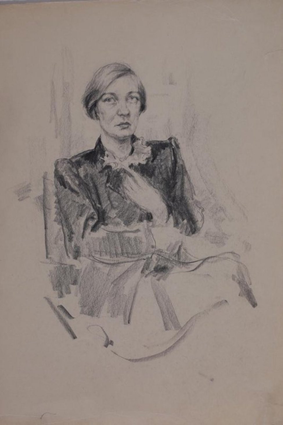 Победренное изображение анфас сидящей женщины с короткой стрижкой, в черном жакете, одна рука на груди, другая - на поясе.