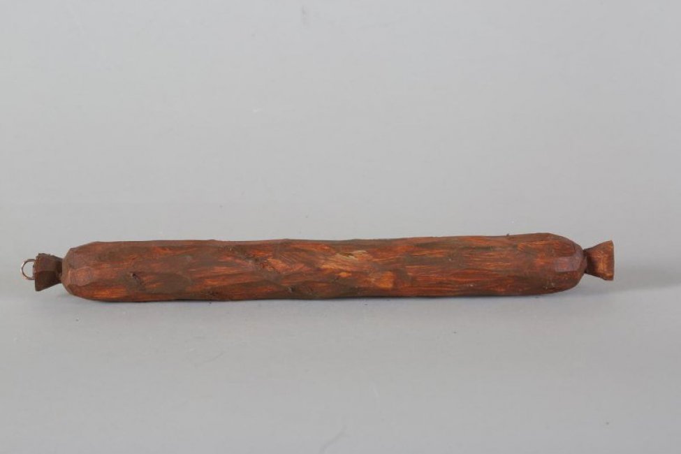 Обобщенное изображение палки копченой колбасы темно-коричневого цвета. С двух сторон - "хвосты" оболочки. С одной стороны, на "хвосте", прикреплено на шуруп металлическое кольцо.