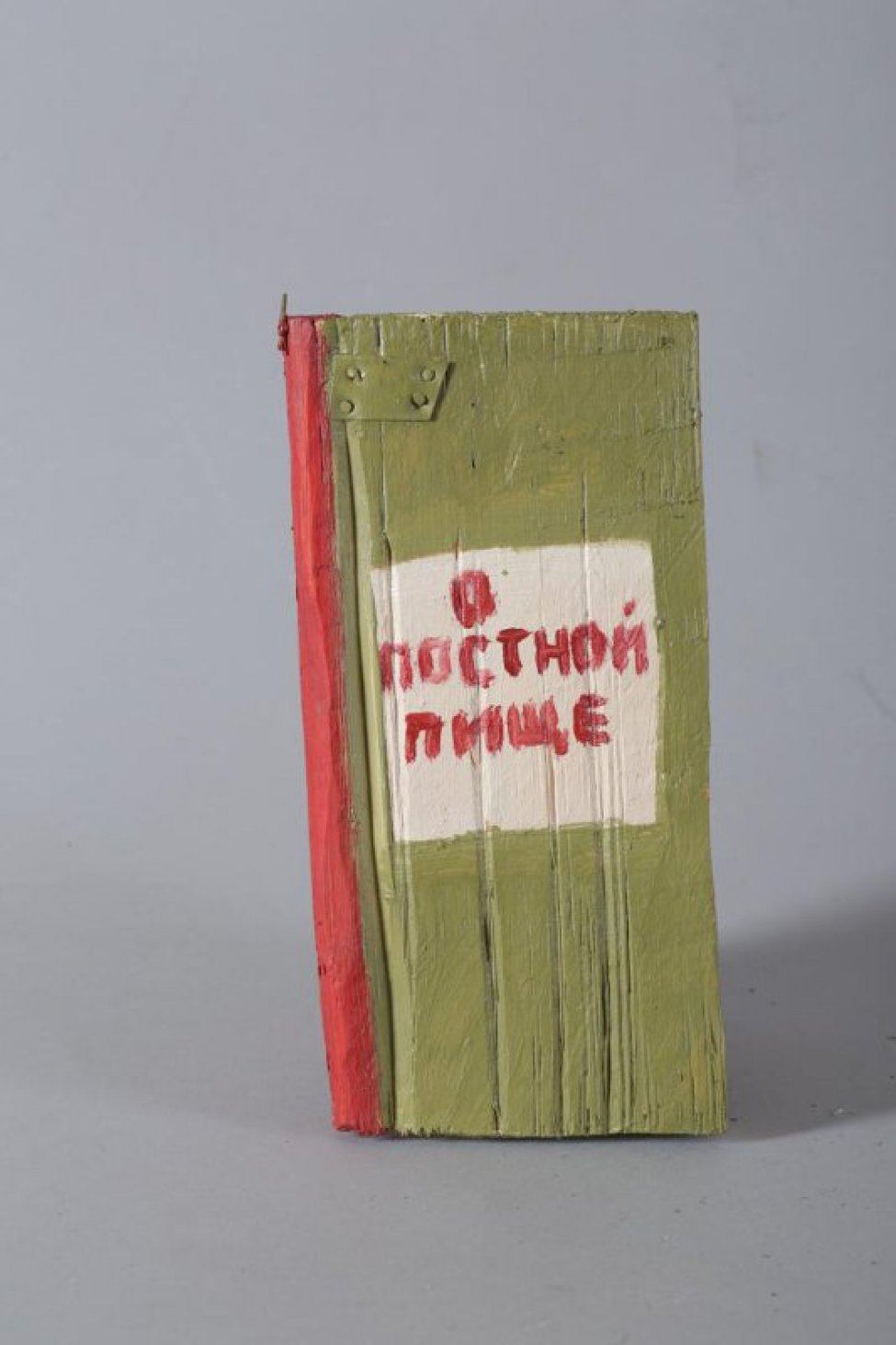Стилизованное изображение книги светло-зеленого цвета с красным корешком. На лицевой стороне белый квадрат с надписью: О постной пище. Страницы обозначены белым цветом.