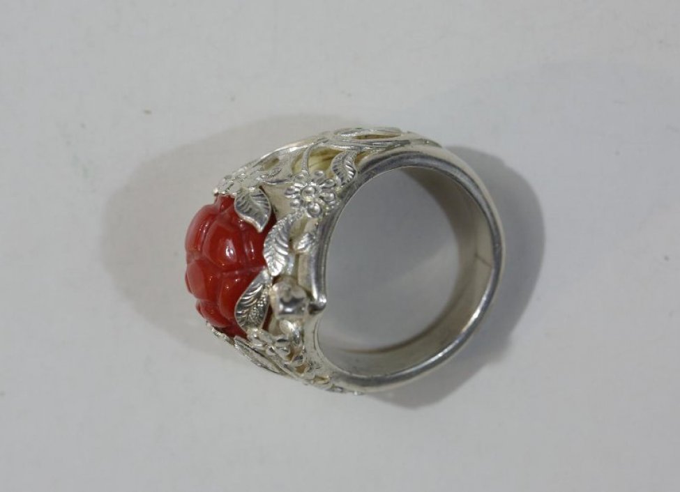 Крупный, тяжелый перстень, с вставленным кораллом в виде ягоды малины. Камень обрамлен веточками с цветами (сквозная резьба).