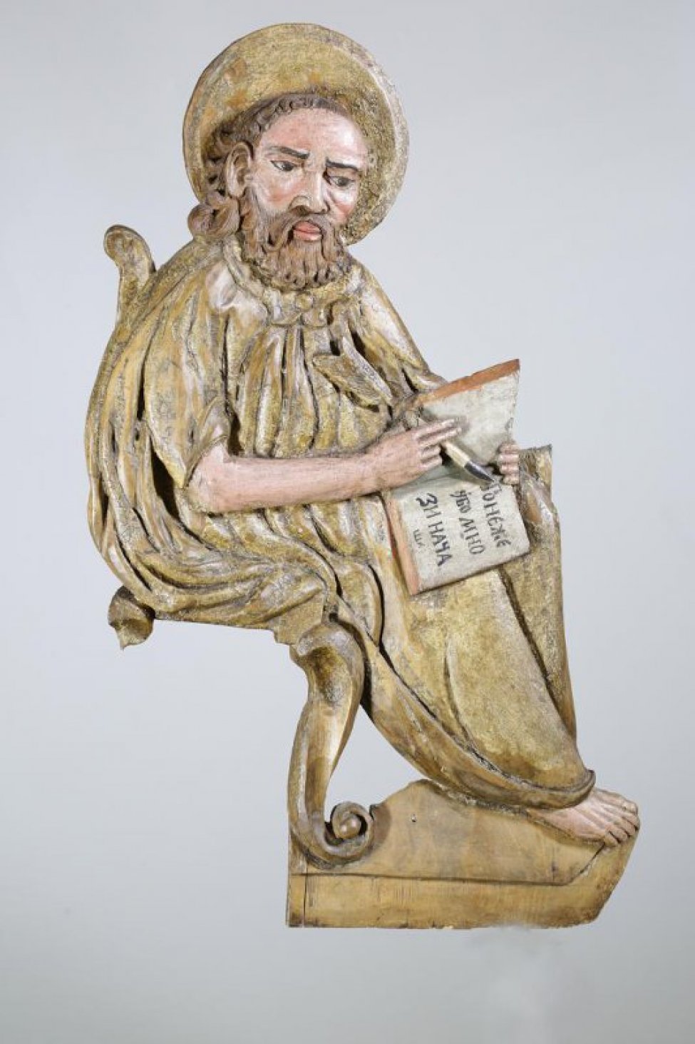 Апостол Лука изображен сидящим, с повернутым влево корпусом. На раскрытой книге написано: "понэже убо...". На голове - нимб. Скульптуру сопровождает изображение тельца.
