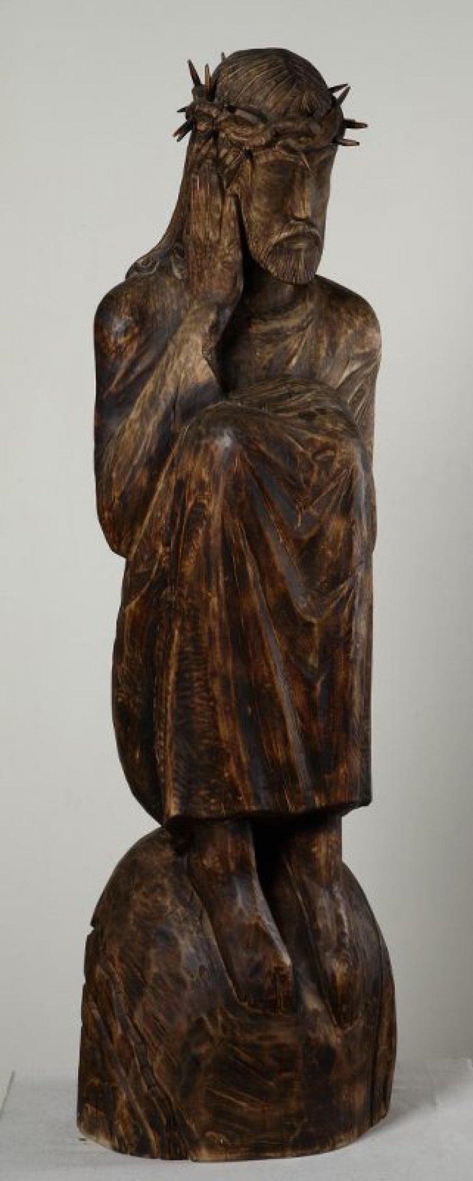 Изображена сидящая фигура Христа в терновом венце, с высоко поднятыми коленями, на полушаре, имитирующем Землю.