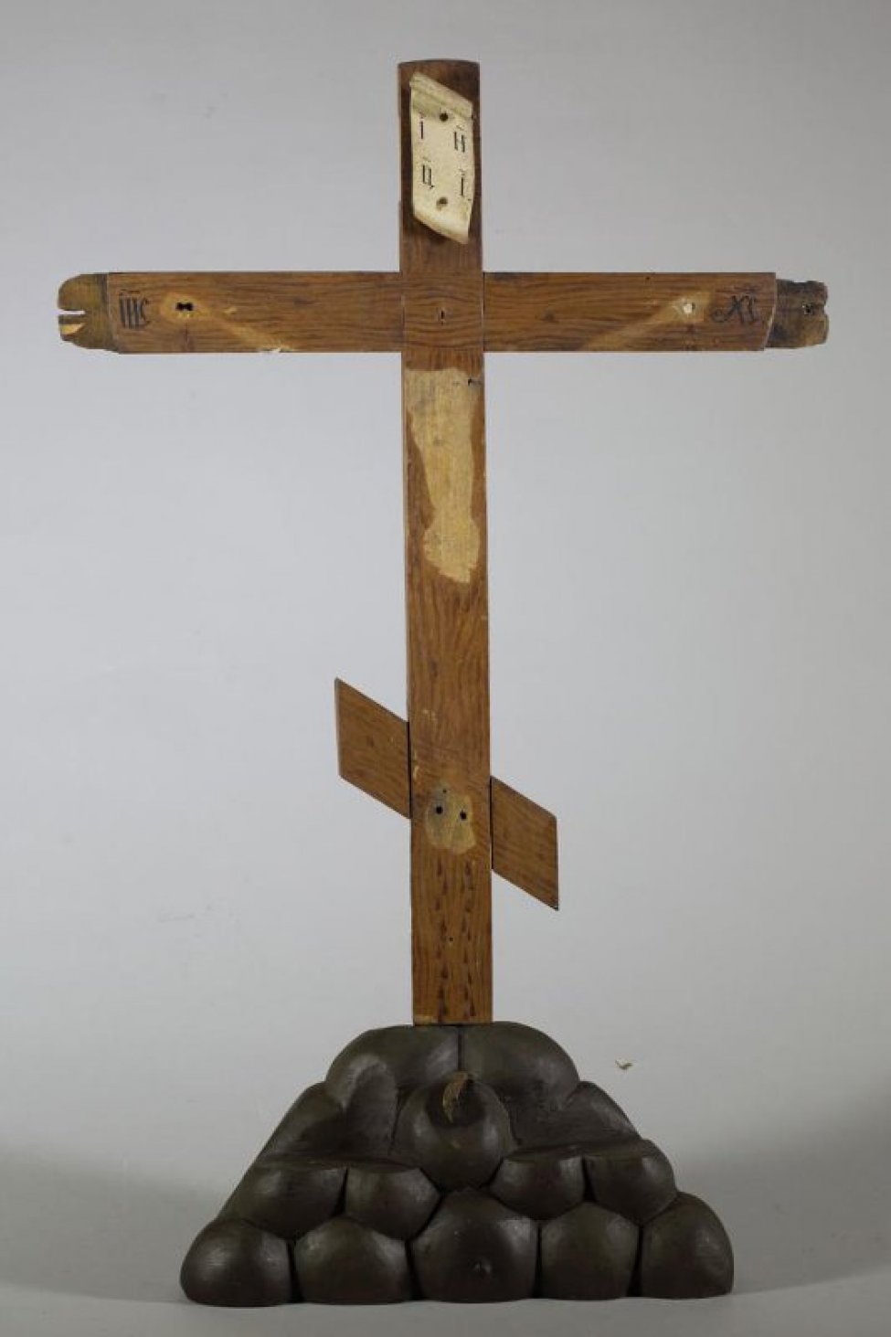 Крест восьмиконечный, с изогнутым свитком и надписью на верху. Внизу креста - подножие (Голгофа) в виде горки.