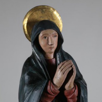 Изображена со сложенными руками и направленными влево, к кресту. На ней красный гиматий и синий хитон.