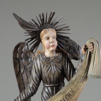 Ангел коленопреклоненный, стоит в нижнем ряду справа. Изображен с поднятой левой рукой и опущенной правой. Одежда посеребрена. Крылья опущенные, посеребренные.