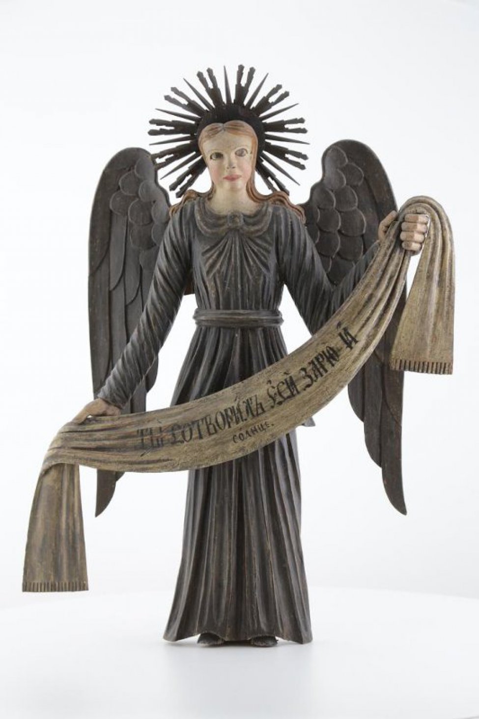 Ангел стоит в нижнем ряду слева в рост. Изображен с поднятой левой рукой и опущенной правой. Одежды: верхняя - позолочена, нижняя - посеребрена. Крылья опущенные, посеребренные.