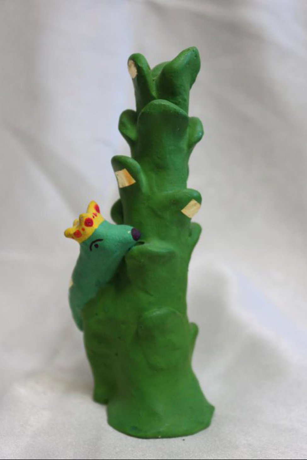 Условное изображение зеленого дерева, на нем ящерица в желтой короне.