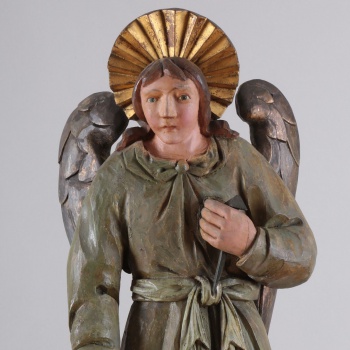 У ангела одежда сине-зеленого цвета. Сзади находится два отдельно вырезанных позолоченных крыла. Правая рука опущена, а левая - поднята.