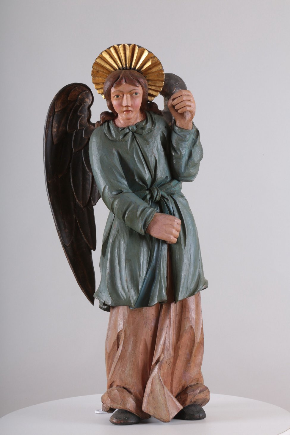 У ангела верхняя одежда синевато-зеленого цвета, нижняя - сиреневого цвета. Сзади находится два отдельно вырезанных позолоченных крыла. Правая рука опущена, а левая - поднята.