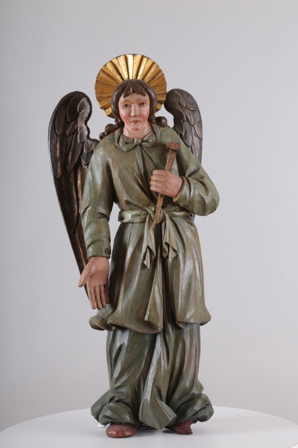 У ангела одежда сине-зеленого цвета. Сзади находится два отдельно вырезанных позолоченных крыла. Правая рука опущена, а левая - поднята.