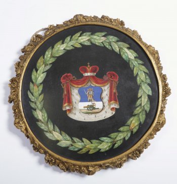 В центре герба - щит, в верхней части которого на синем фоне изображён 
