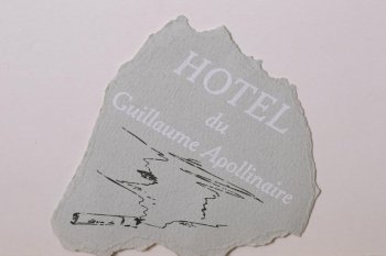 На обрывке серой плотной бумаги изображена дымящаяся папироса, выше - надпись белым цветом на французском языке 