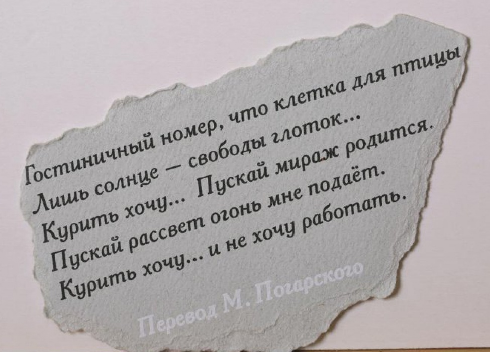 На обрывке серой плотной бумаги  текст черной краской в пять строк на русском языке, внизу - фраза "Перевод М. Погарского" выполнена белым.