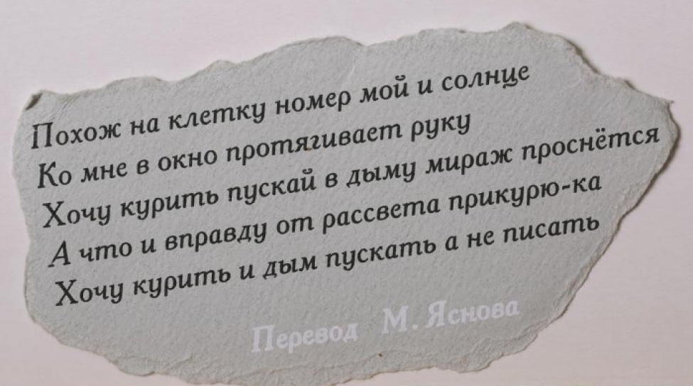 На обрывке серой плотной бумаги  текст черной краской в пять строк на русском языке, внизу - фраза "Перевод М. Яснова" выполнена белым.