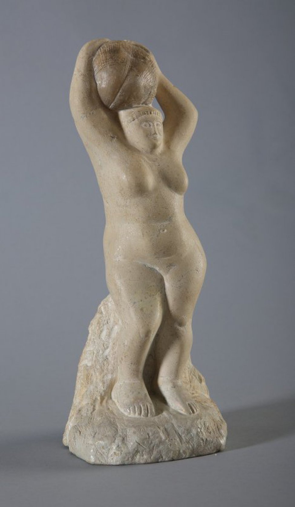 Изображена обнаженная женская фигура в рост, присевшая на камень, играющий роль постамента. Правая нога согнута в колене. На голове обеими руками держит камень с отпечатком раковины - аммонит.