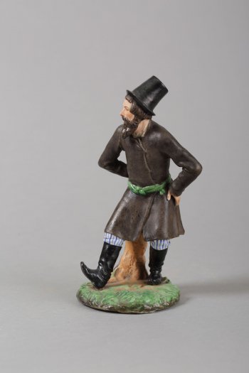 На круглом зеленом постаменте изображен пляшущий крестьянин с черной бородой, в черном кафтане с зеленой опояской, полосатых штанах. На ногах сапоги, на голове черная шляпа.