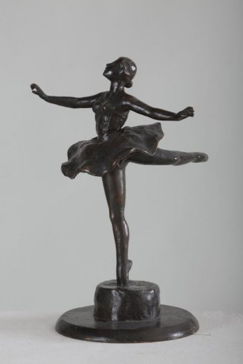 Изображена балерина  в рост. Она стоит на носке правой ноги, левая под прямым углом поднята кверху, голова откинута назад, обе руки отведены в стороны. На балерине одета  пышная балетная пачка.