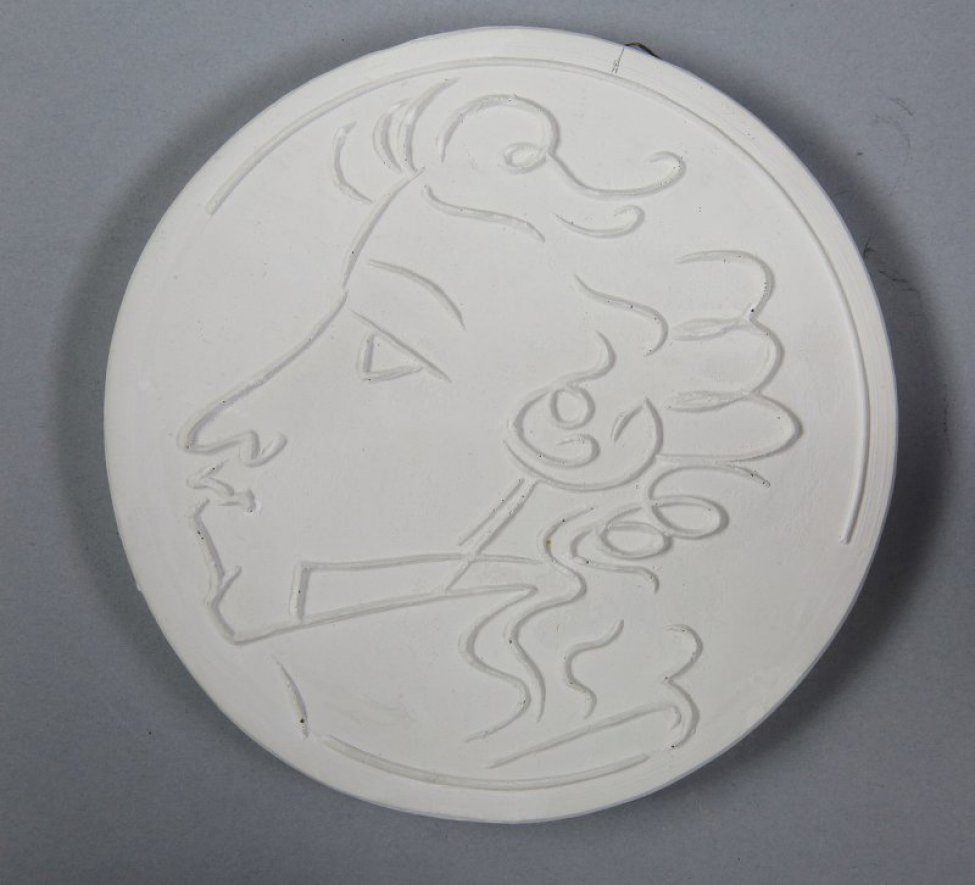 Профильное изображение головы молодого Пушкина. Лицо, волосы, поднятый воротник выполнены невысоким рельефом.