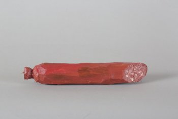Обобщенное изображение части палки копченой колбасы в оболочке темно-красного цвета, с небольшими корчневыми мазками. С одной стороны 