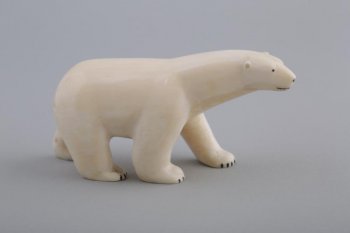 Фигурка идущего белого медведя. Правые его лапы вместе, левые - широко расставлены. Голова чуть повернута вправо. Глаза, рот и когти намечены черной краской.