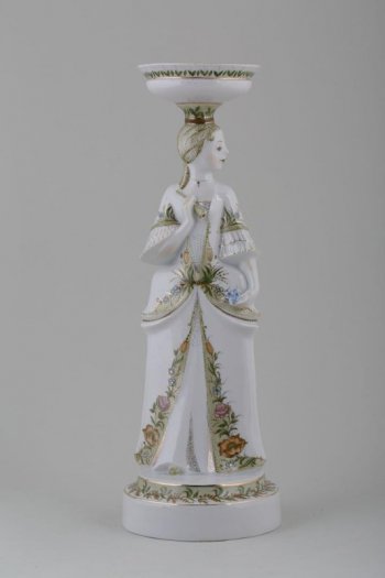 На круглом постаменте изображена девушка с вазоном на голове, в руке - дудочка. Платье, вазон и постамент расписаны цветочным орнаментом.