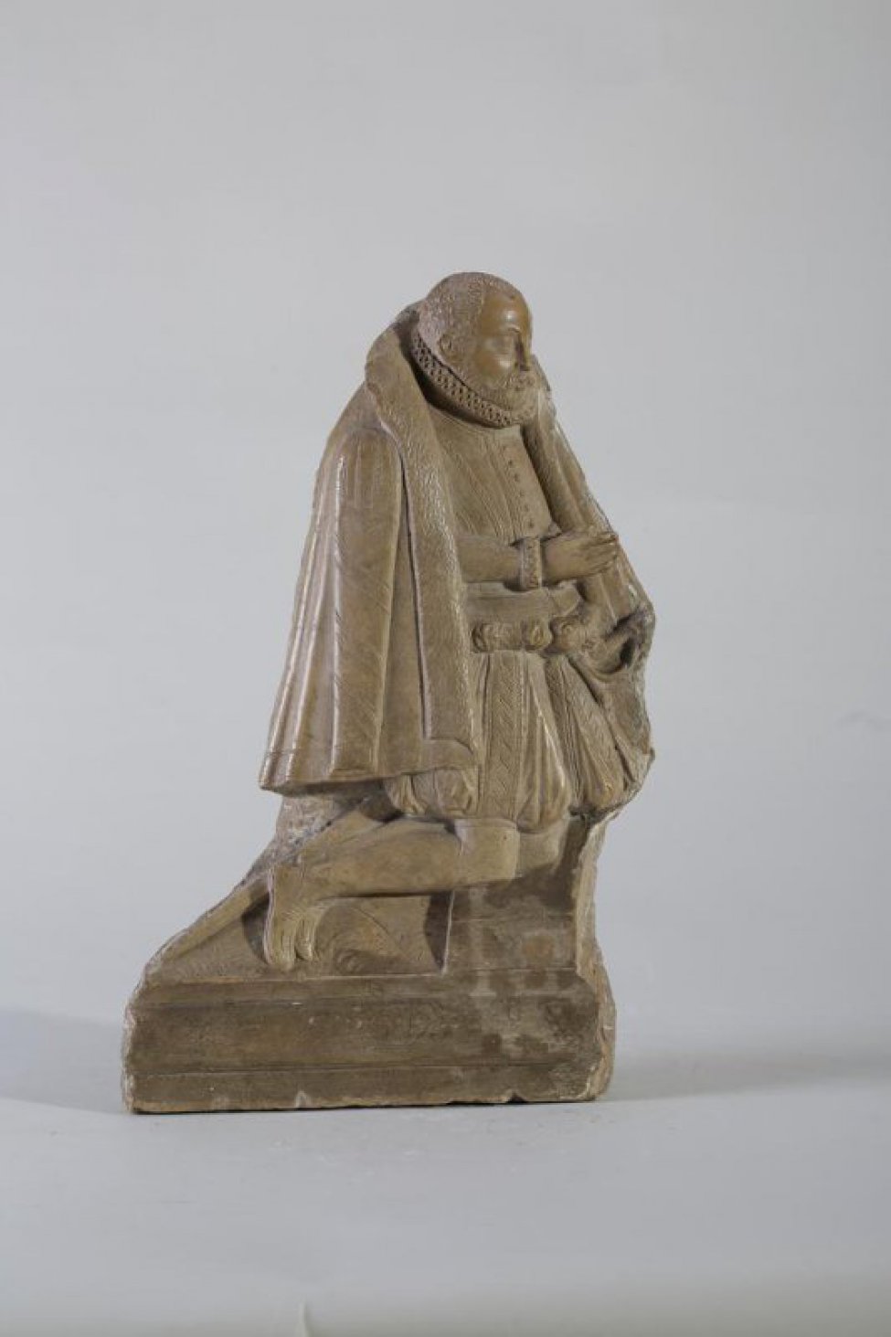 Изображена коленопреклоненная фигура молящегося мужчины, на каменных ступенях. Мужчина изображен в правый профиль. Руки сложены вместе и подняты для молитвы. На плечах накидка.