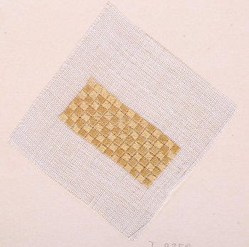 На образце квадратной формы из ткани редкого переплетения серого цвета в центре дан прямоугольный образец вышивки жёлтого цвета: мелкие квадратики шитые по диагонали создают плотный шахматный узор. Образец приклеен на картонный лист.