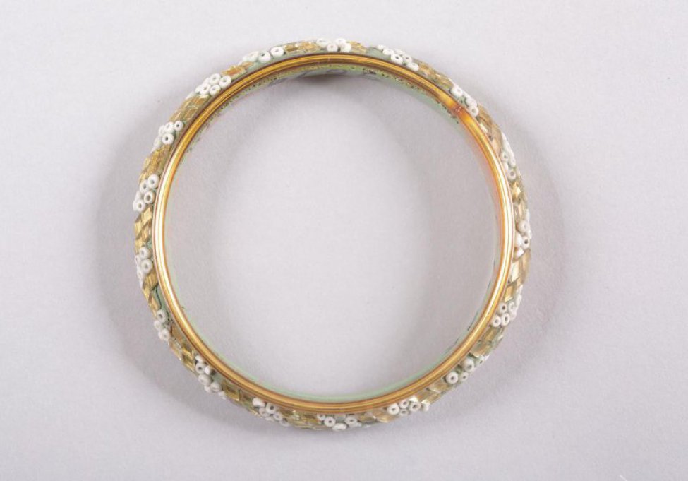 Круглый бирюзовый. Внешняя выпуклая сторона украшена белым бисером и золотистыми кусочками зеркала в виде ромбов, по краям браслета - золотистые ободки.