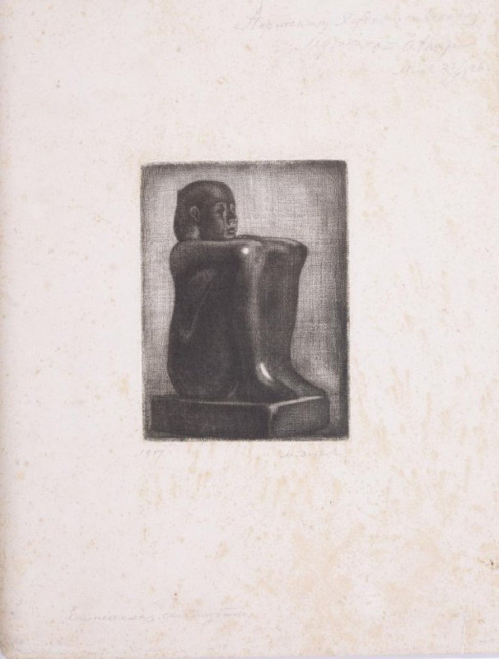Статуэтка изображает женщину, сидящую на пьедестале с согнутыми в коленях ногами. Руки лежат на коленях.