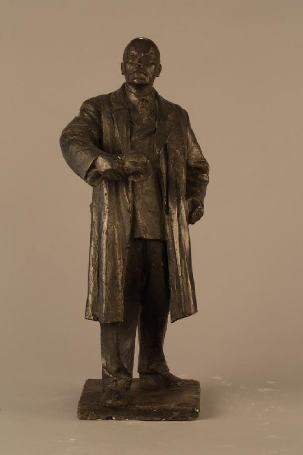 Фигура стоит на квадратном постаменте. Ленин одет в черный костюм и пальто. Правая его нога выдвинута вперед. В правой руке, немного согнутой в локте и вытянутой вперед - перед собой, сжата кепка. Большой палец левой руки заложен в карман пальто.