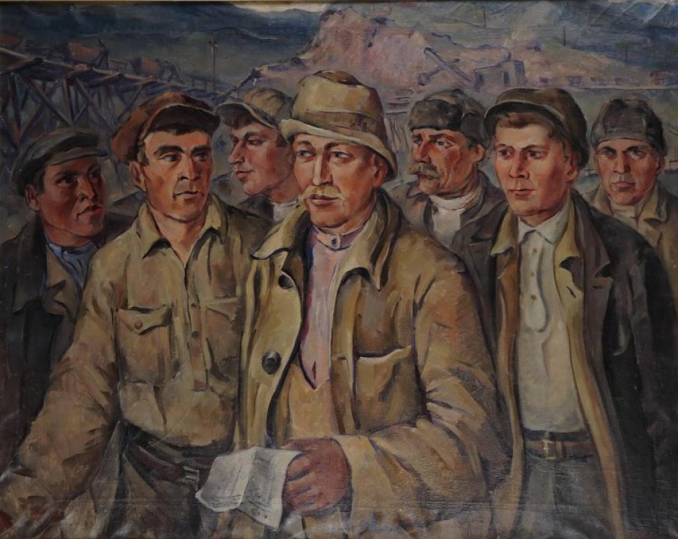 Поясное изображение группы рабочих, одетых в шахтерские спецовки, с бригадиром Багаутдиновым в центре, с листом бумаги в руках. Вдали горы слева деревянный мост.