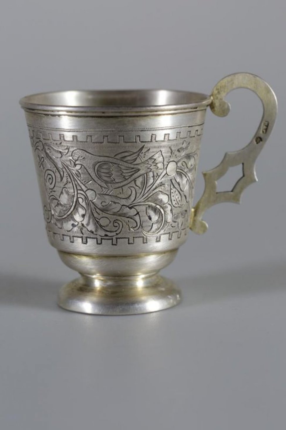 Чашка серебряная с гравировкой по тулову. Орнамент растительный, с изображением двух птиц на веточках.