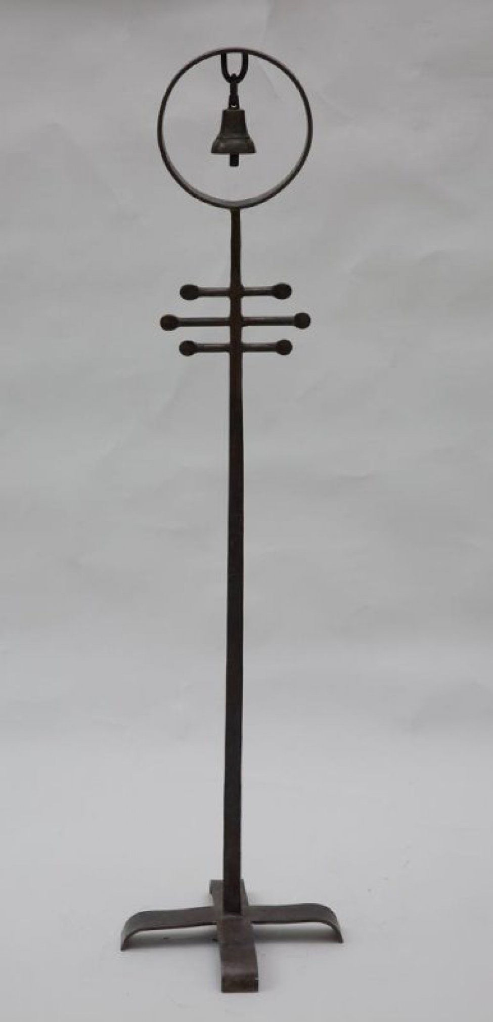 На крестообразном основании на вертикальном стержне в круге изображен колокол, подвешенный на петлю за кольцо.