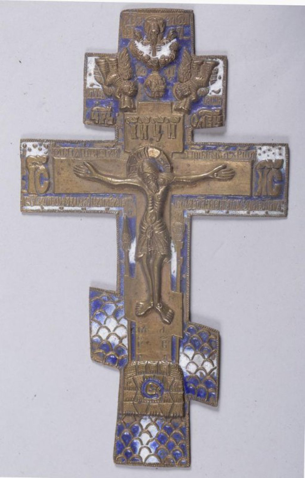 Крест четырехконечный с изображением Распятия, Господа Саваофа и двух плачущих ангелов. Эмаль двухцветная: синего и белого цвета. На обороте - тропарь.