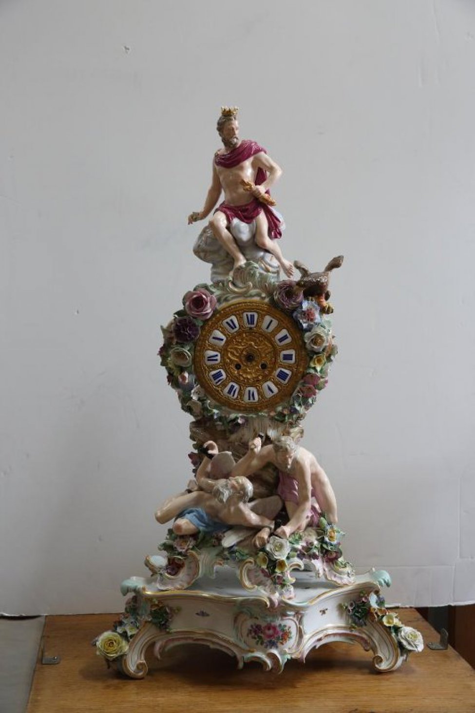Часы с бронзовым циферблатом, в фарфоровом футляре, со скульптурами людей и лепными цветами.