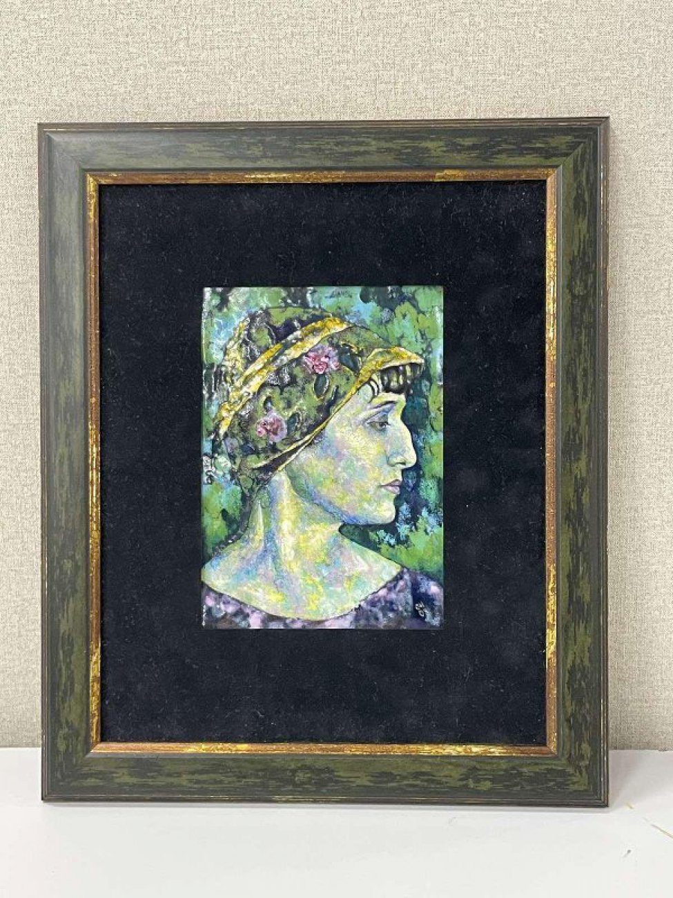 На фоне зелени изображен оплечный портрет Анны Ахматовой в профиль вправо. На голове шляпка. В правом нижнем углу авторская монограмма"СН 08".