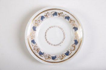 Тарелка с горошчатым краем, белая. На зеркале каемка золоченого растительного орнамента. Борт расписан синими мелкими ягодами с золочеными листьями.